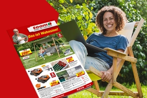 Eine Person sitzt lächelnd mit einem Laptop in einem Gartenstuhl.